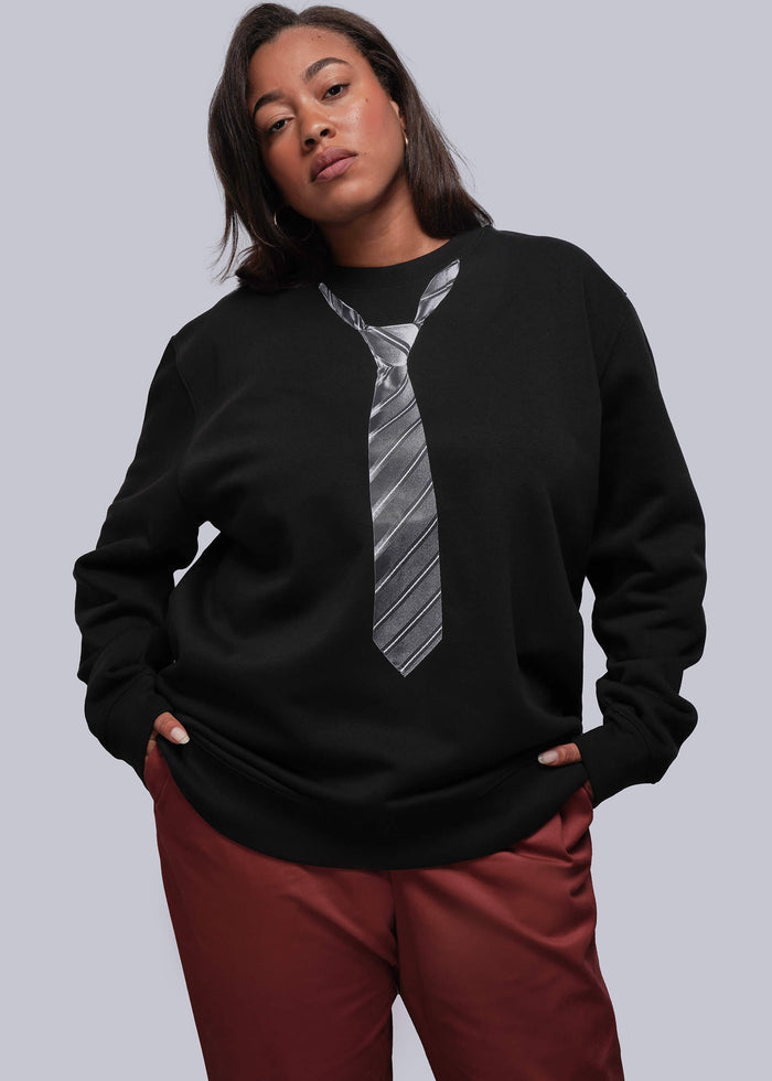 1X=Person wearing a black sweatshirt with a tie design and red orange colored pants on a gray background
