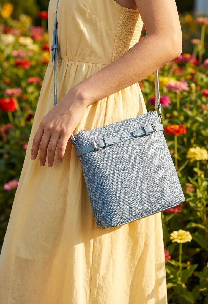 Person holding a blue textured handbag with a floral background