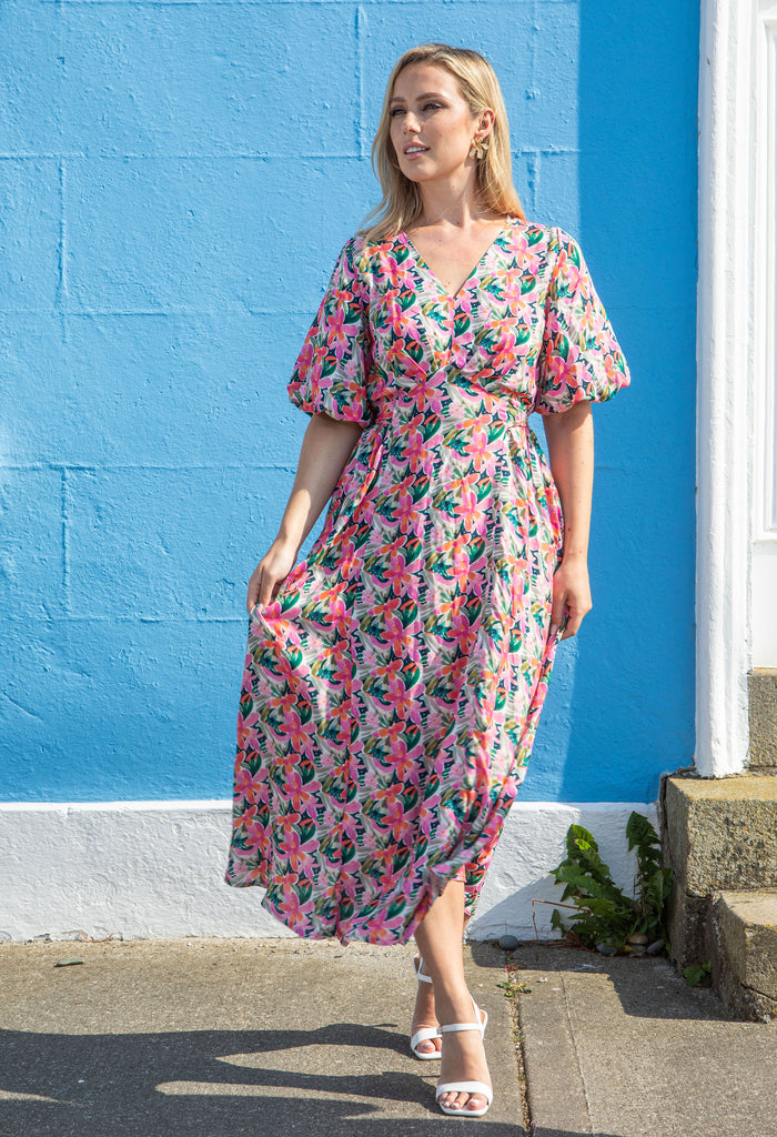 Woman in a floral dress standing against a blue wall